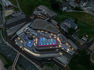 Aerial view of the illuminated Silvretta Therme in Ischgl at night.