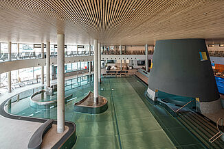 Indoor pool with relaxation area and loungers at the Silvretta Therme in Ischgl.