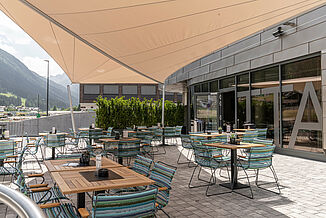 Terrace with tables and chairs in the outdoor area of the Silvretta Therme in Ischgl.