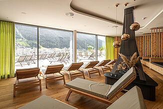 Modern relaxation area of the Silvretta Therme with large glass front and view of the terrace and the mountains.